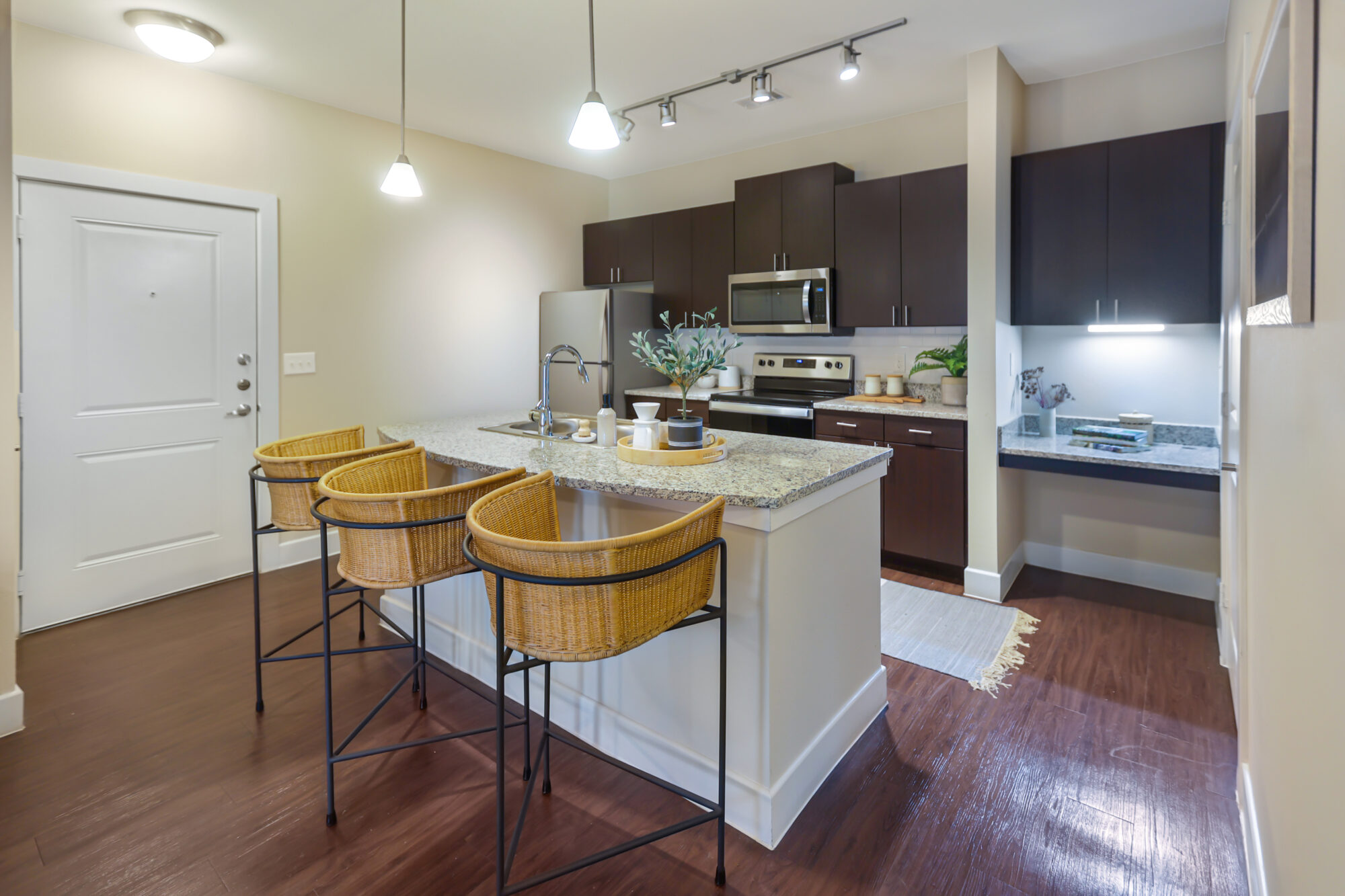 Kitchen with stainless steel appliances, granite counters, tile backsplash, and built in desk